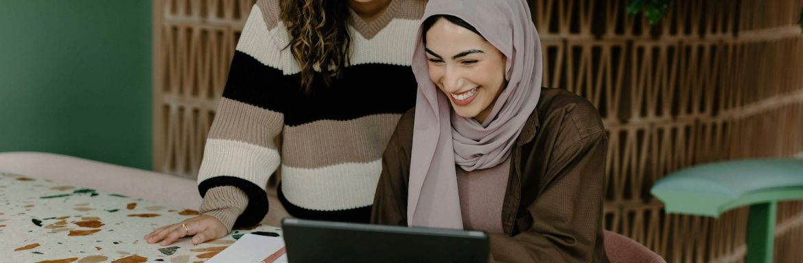 Two women sitting at a table with a laptop
